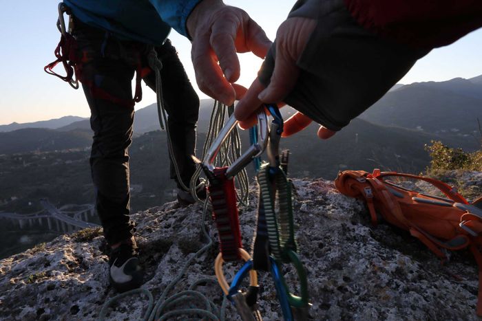 En klättrare räcker över sin utrustning till en kamrat.